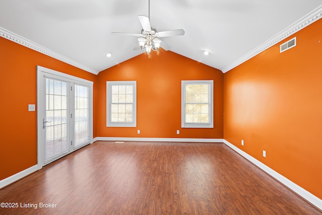 empty room with vaulted ceiling, wood finished floors, baseboards, and ornamental molding