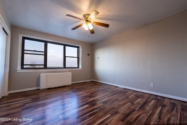 spare room with a ceiling fan, radiator heating unit, baseboards, and wood finished floors