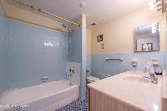 bathroom with visible vents, a wainscoted wall, toilet, bathtub / shower combination, and tile walls