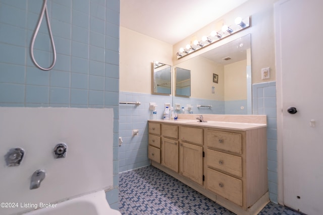 full bath with wainscoting, a washtub, tile walls, and vanity