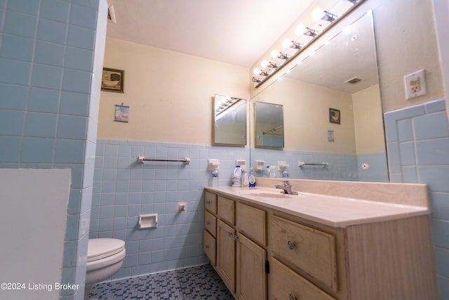 bathroom with vanity, visible vents, a wainscoted wall, tile walls, and toilet