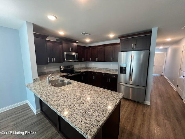 kitchen featuring light stone counters, visible vents, appliances with stainless steel finishes, and a peninsula