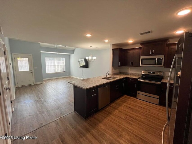 kitchen featuring visible vents, open floor plan, wood finished floors, stainless steel appliances, and an inviting chandelier