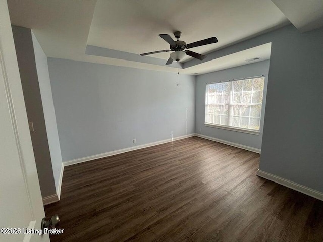 unfurnished room featuring visible vents, a raised ceiling, dark wood-type flooring, baseboards, and ceiling fan