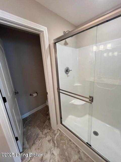 full bathroom featuring baseboards, toilet, and a stall shower