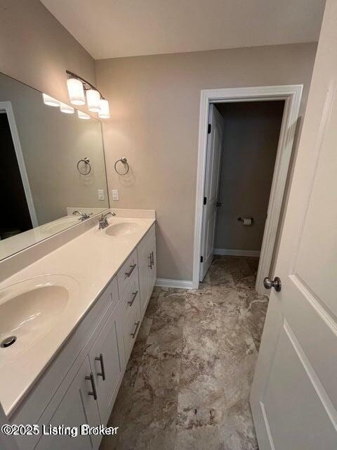 bathroom featuring double vanity, baseboards, and a sink