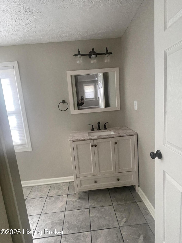 bathroom featuring baseboards, a textured ceiling, and vanity