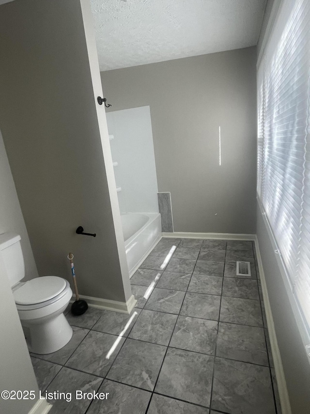 full bathroom featuring visible vents, a textured ceiling, toilet, and baseboards