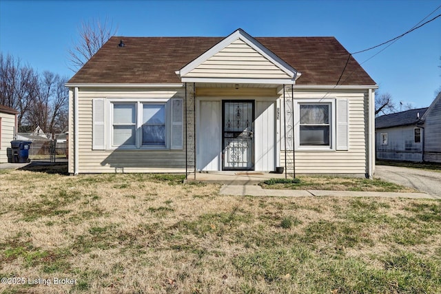 view of front facade with a front yard and roof with shingles