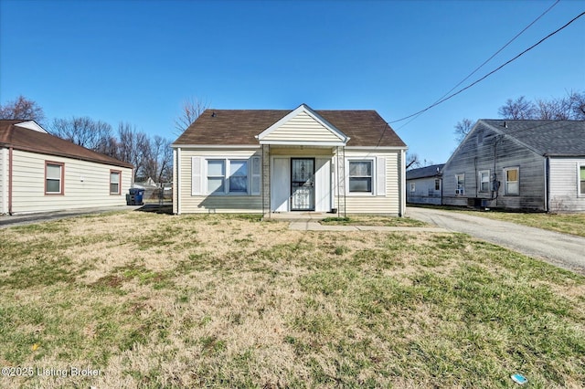 bungalow with aphalt driveway and a front lawn