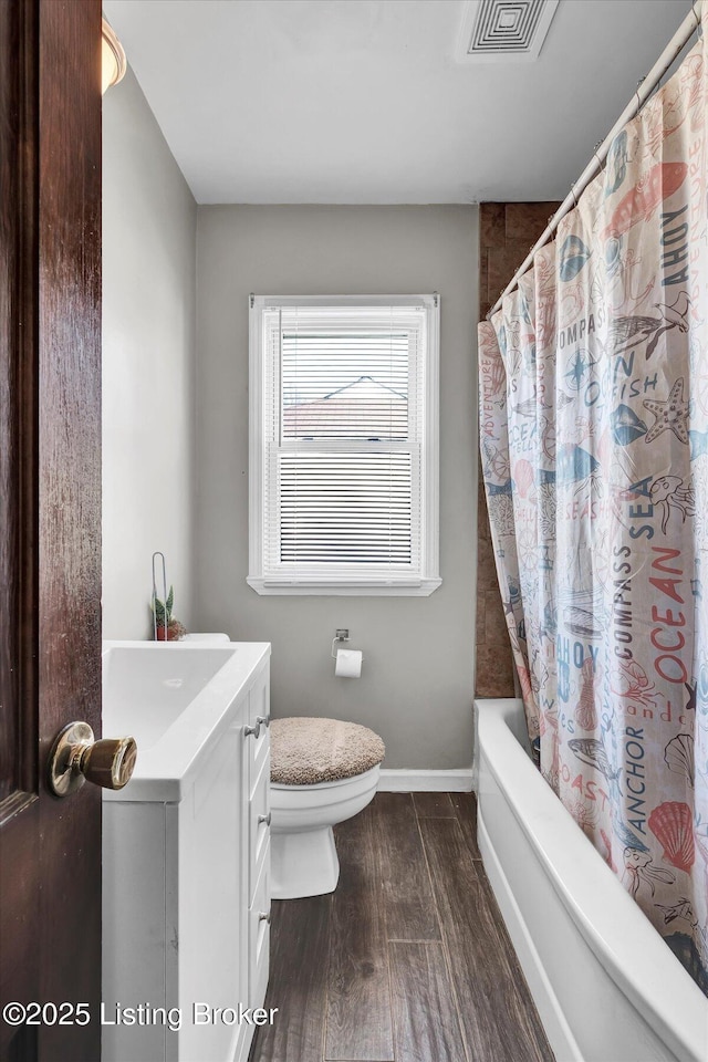 full bath with wood finished floors, visible vents, baseboards, shower / bath combo, and toilet