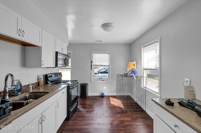 kitchen with stainless steel microwave, black range with electric cooktop, dark wood-type flooring, white cabinets, and a sink