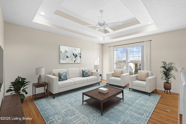 living area with a raised ceiling, wood finished floors, and baseboards