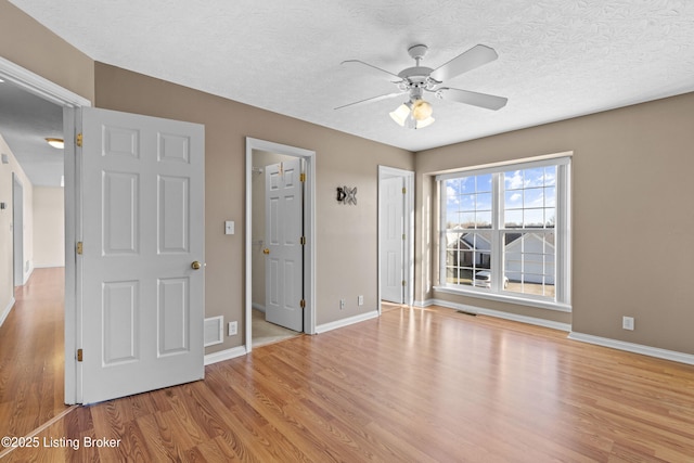 unfurnished bedroom featuring visible vents, baseboards, a textured ceiling, and wood finished floors