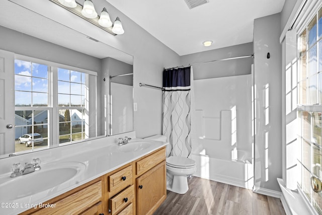 bathroom with a sink, toilet, wood finished floors, and shower / tub combo with curtain