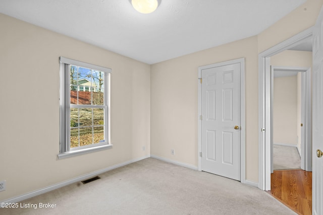 unfurnished bedroom featuring baseboards, visible vents, and light carpet