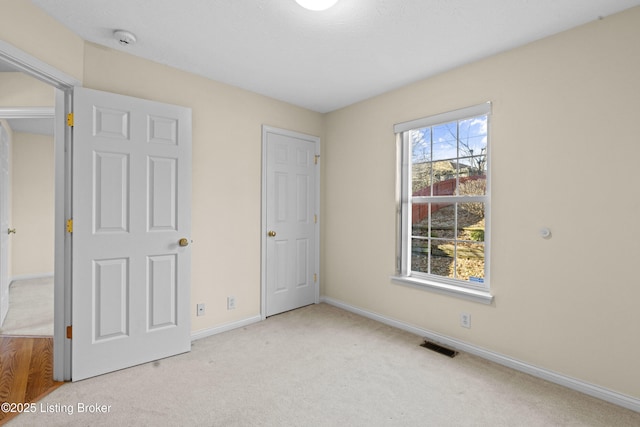 unfurnished bedroom featuring baseboards, carpet floors, and visible vents