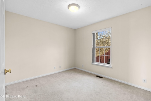 carpeted spare room featuring baseboards and visible vents