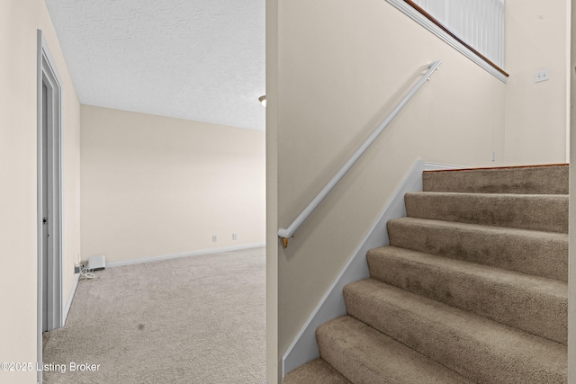 staircase with baseboards, carpet floors, and a textured ceiling