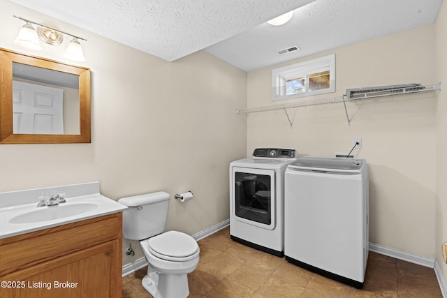 bathroom with visible vents, toilet, vanity, a textured ceiling, and separate washer and dryer