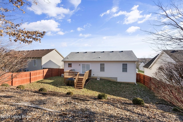 rear view of house featuring a wooden deck, a yard, a fenced backyard, a shingled roof, and stairs