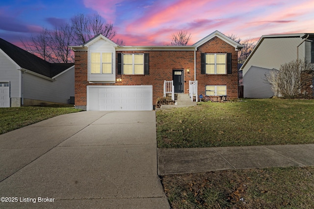 raised ranch with brick siding, a garage, driveway, and a front yard