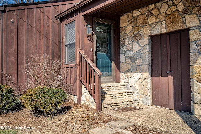 view of exterior entry featuring stone siding and board and batten siding