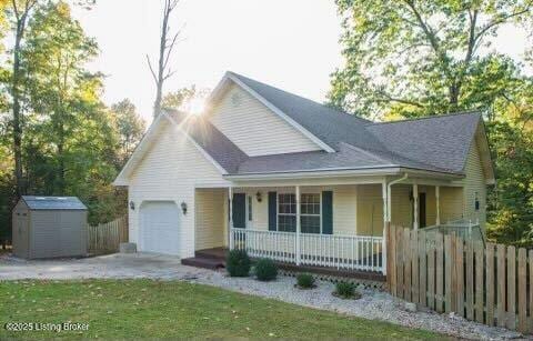 view of front of house featuring a storage shed, a garage, fence, and covered porch