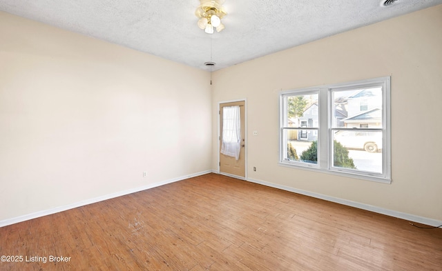 spare room with a textured ceiling, wood finished floors, baseboards, and ceiling fan