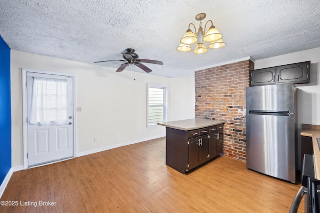 kitchen featuring freestanding refrigerator, light countertops, a textured ceiling, ceiling fan with notable chandelier, and light wood-type flooring