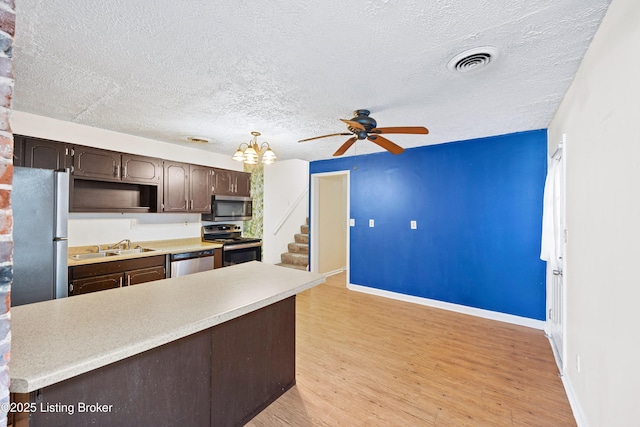 kitchen with visible vents, stainless steel appliances, dark brown cabinetry, light countertops, and ceiling fan with notable chandelier