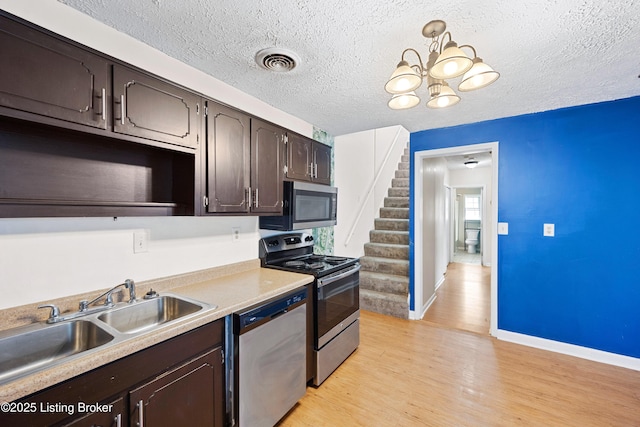 kitchen featuring visible vents, light wood-style flooring, a sink, stainless steel appliances, and dark brown cabinetry