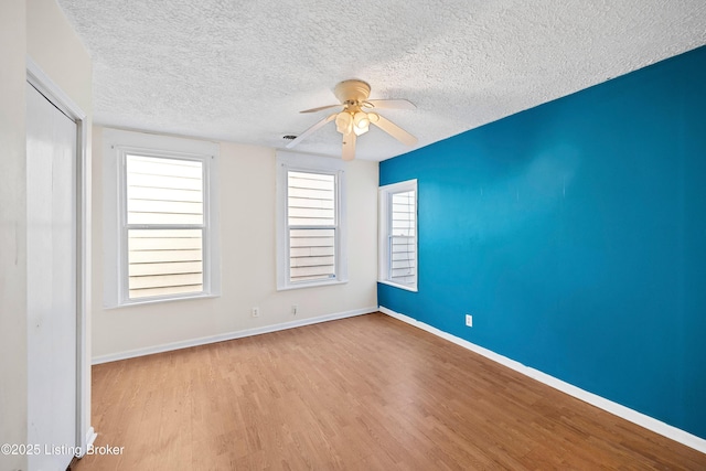 unfurnished room with baseboards, a textured ceiling, wood finished floors, and a ceiling fan