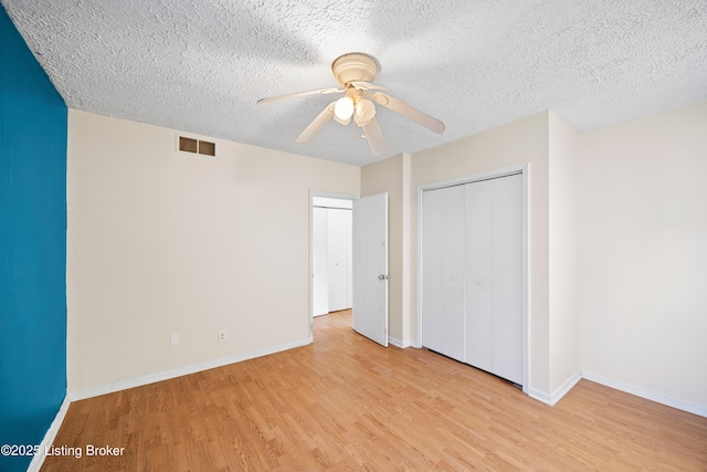 unfurnished bedroom featuring a closet, visible vents, baseboards, and light wood-style floors