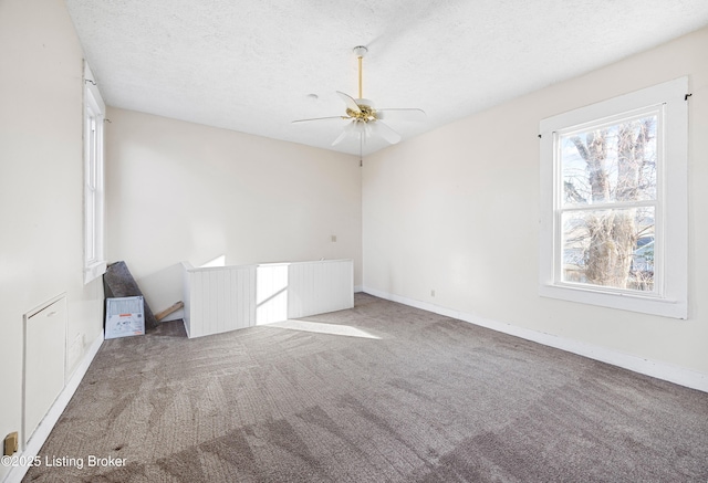 carpeted spare room featuring baseboards, a textured ceiling, and a ceiling fan