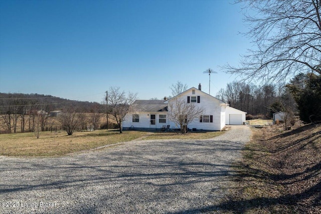 view of front of house with gravel driveway and a front lawn