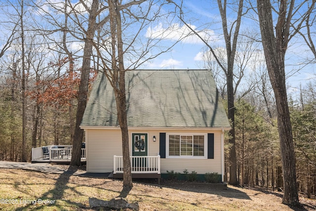 cape cod-style house featuring a shingled roof and a deck