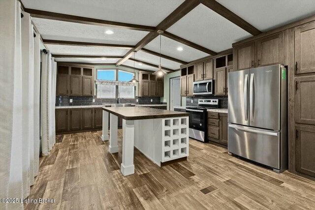 kitchen with stainless steel appliances, decorative backsplash, vaulted ceiling with beams, and light wood finished floors