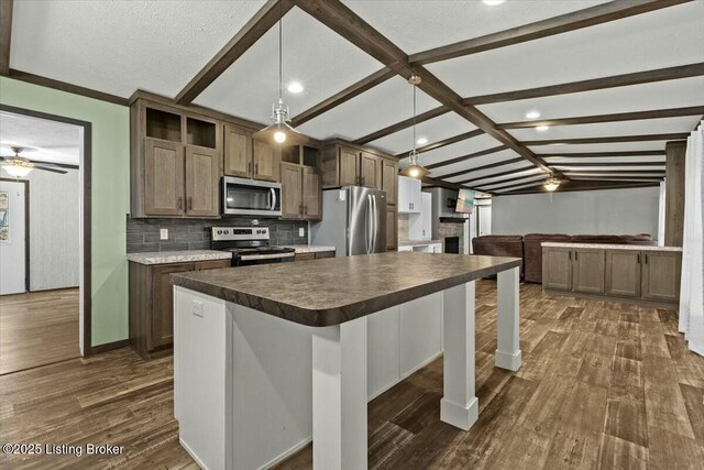 kitchen with dark wood finished floors, dark countertops, tasteful backsplash, and appliances with stainless steel finishes