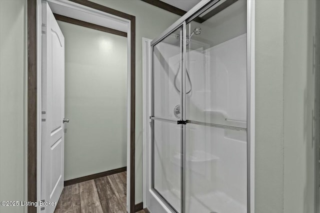 full bath featuring baseboards, wood finished floors, and a stall shower