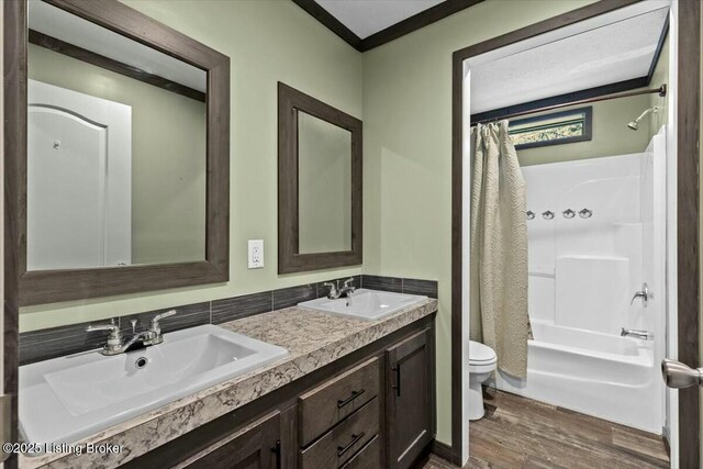 bathroom with a sink, toilet, wood finished floors, and double vanity