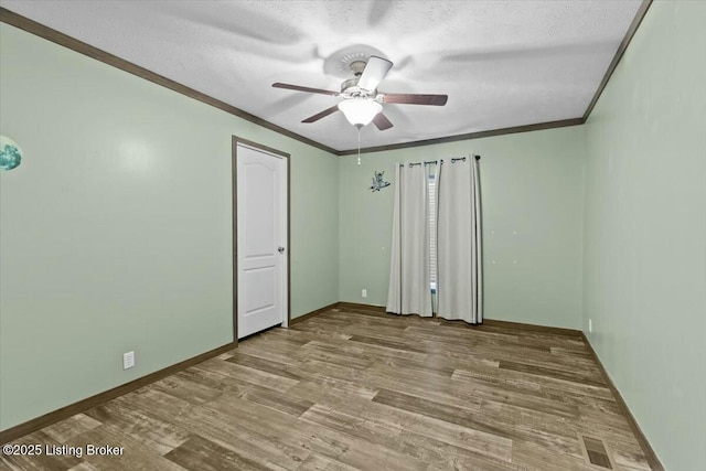 unfurnished bedroom with ceiling fan, baseboards, ornamental molding, wood finished floors, and a textured ceiling