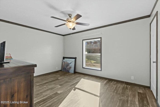 unfurnished room with a ceiling fan, crown molding, wood finished floors, and baseboards