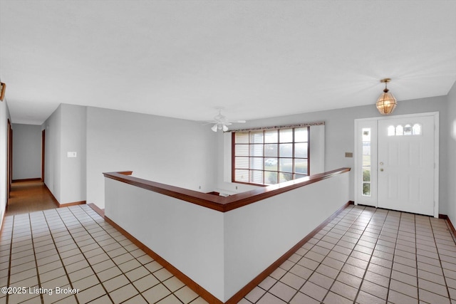 entryway featuring light tile patterned floors, ceiling fan, and baseboards