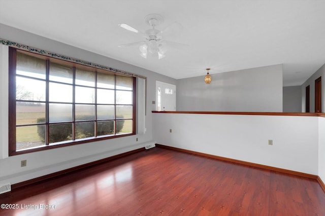 unfurnished room featuring visible vents, a ceiling fan, baseboards, and wood finished floors