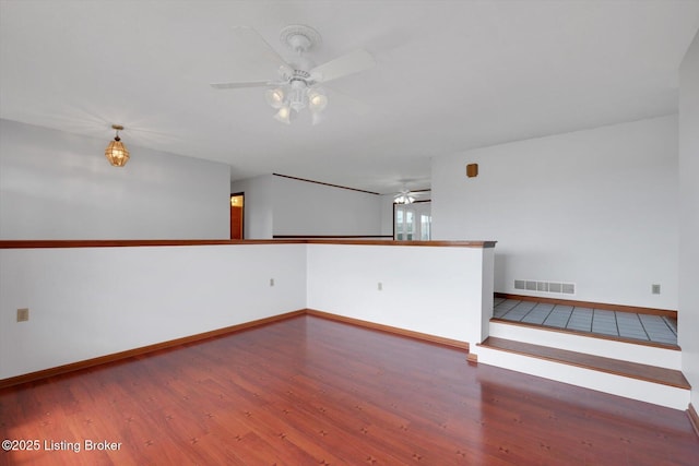 spare room with ceiling fan, wood finished floors, visible vents, and baseboards