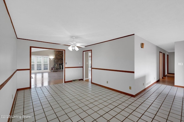 empty room featuring light tile patterned floors, baseboards, visible vents, ornamental molding, and ceiling fan