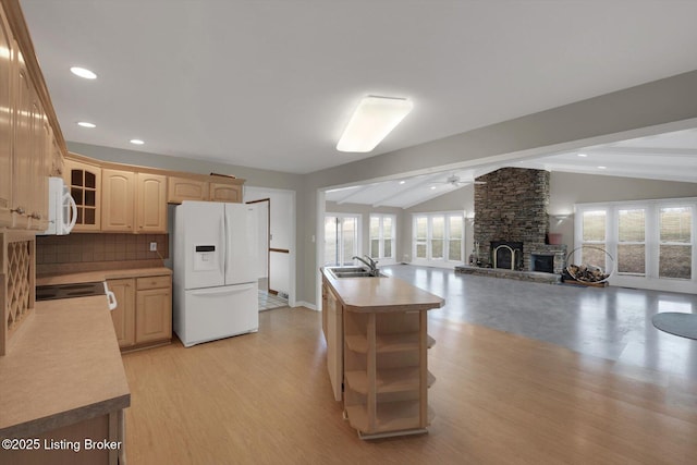 kitchen featuring light countertops, lofted ceiling with beams, a stone fireplace, white appliances, and a sink