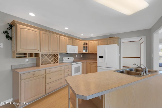 kitchen with light brown cabinets, white appliances, tasteful backsplash, and a sink