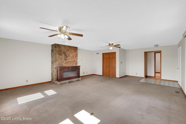 unfurnished living room featuring a stone fireplace, carpet flooring, visible vents, and baseboards